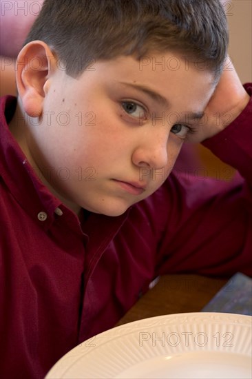 USA, Minnesota, St Paul, Defiant and hungry young boy age 8 waiting for brunch.