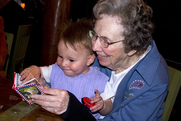 USA, Minnesota, Plymouth, Great grandmother reading book to great grandson in Red Lobster restaurant.