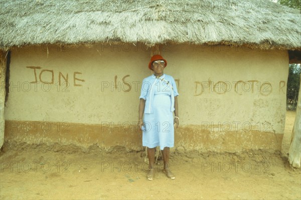 BOTSWANA, People, Traditional healer standing outside thatched hut with ‘Jane is a doctor’ written across the wall.