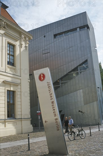 GERMANY, Berlin, Visitors walking past entrance to the Jewish Museum designed by Polish architect Daniel Libeskind in 1998 with name sign in foreground.
