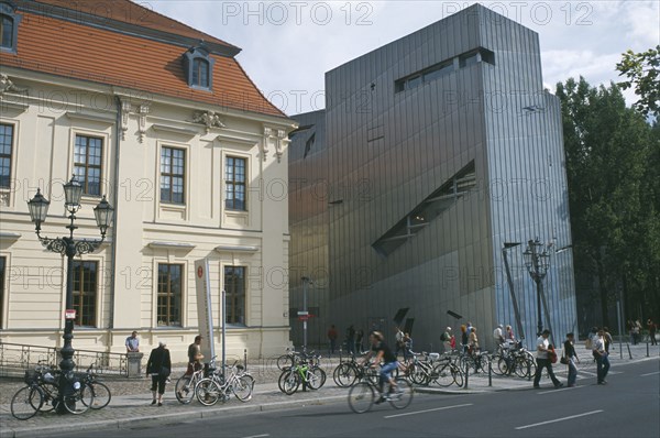 GERMANY, Berlin, Visitors at entrance to the Jewish Museum designed by Polish architect Daniel Libeskind situated beside traditional building with bicycles chained up outside.