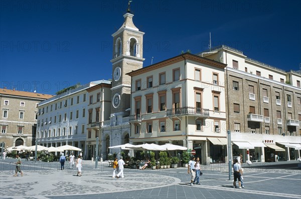 ITALY, Emilia-Romagna, Rimini, Town square with church and clock tower and cafes with outside tables.