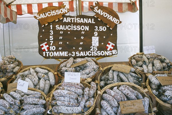FRANCE, Rhone Alps, Haute Savoie, Samoens.  Baskets of different flavoured pork sausages for sale on market stall.