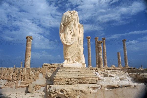 LIBYA, Tripolitania, Sabratha, Headless and armless classical statue on raised plinth with standing columns behind