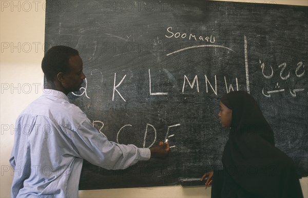 SOMALILAND, Hargeisa, Teacher and pupil writing letters on blackboard at school for returnees in Kandahar settlement.
