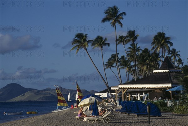WEST INDIES, Nevis, View along beach with sails and sunbeds beside beach bars of the Four Seasons Hotel