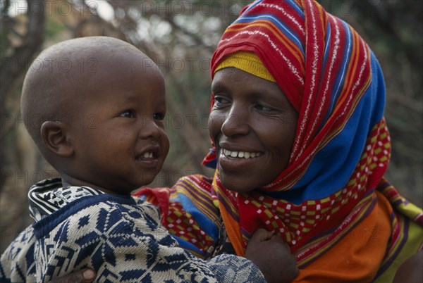 SOMALIA, Near Hargeisa, Portrait of mother wearing colourful headscarf holding and looking at her child