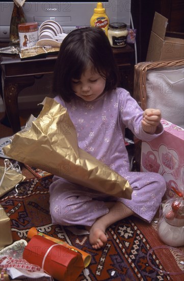 FESTIVALS, Christmas, Presents, Five year old girl sitting on the floor opening her Christmas presents
