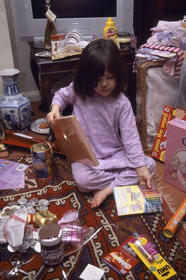 FESTIVALS, Christmas, Presents, Five year old girl sitting on the floor opening her Christmas presents