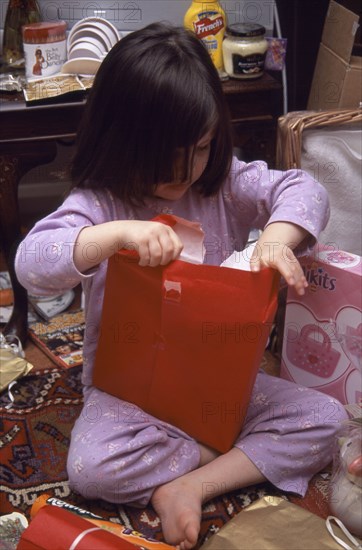 FESTIVALS, Christmas, Presents, Five year old girl sitting on the floor opening her Christmas presents