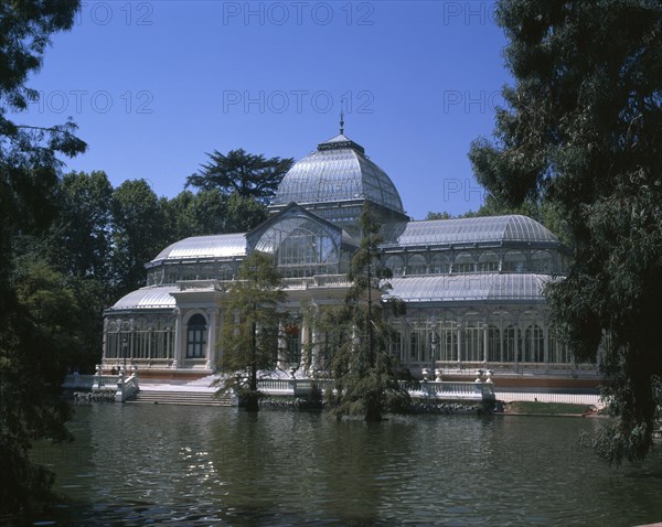 SPAIN, Madrid State, Madrid , Retiro Park. The Crystal Palace surrounded by trees seen from across pond.