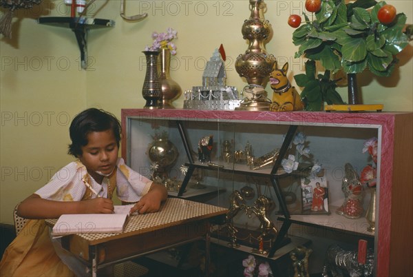 INDIA, Madhya Pradesh, Education, Ten year old girl doing homework in sitting room of middle class home.