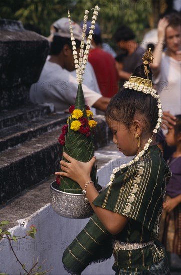 LAOS, Luang Prabang, Young girl in traditional dress with flower offering during New Year celebrations.