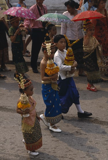LAOS, Luang Prabang, Children in traditional dress carrying offerings at New Year celebrations.