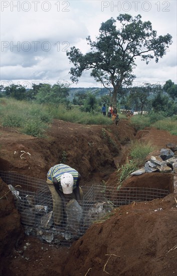 TANZANIA, West, Great Lakes Region, Refugees making gambions from stone filled wire cages to prevent water erosion.
