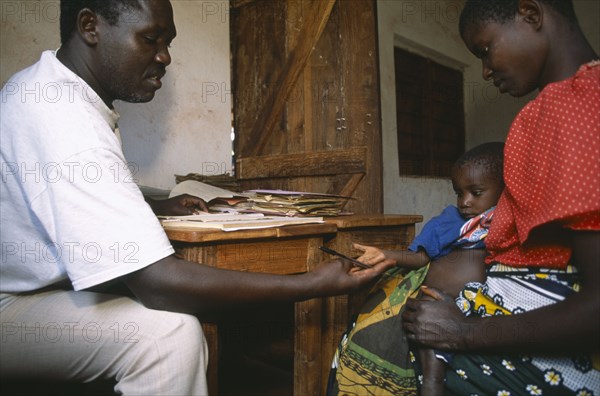 TANZANIA, West, Great Lakes Region, Refugee camp health centre.  Male staff with woman and child.