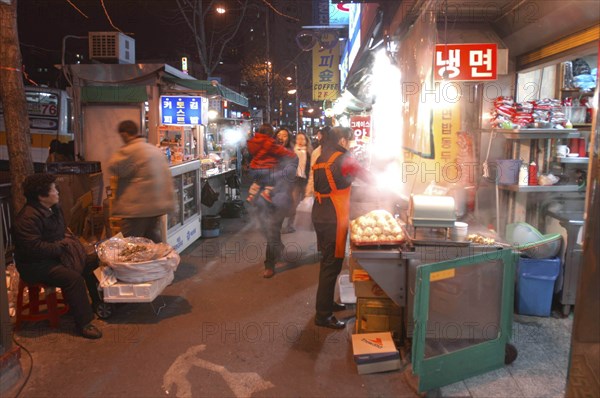 KOREA, Seoul, Namdaemun Market on a cold December night with street vendors and a young woman carrying a baby