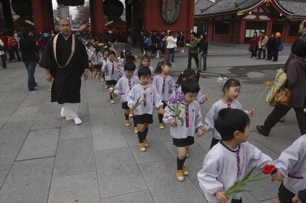 JAPAN, Honshu, Tokyo, "Asakusa. 4 year old nursery students from Senso-ji Dembo-in Nursery, carrying flowers to present to Buddha as part of his birthday celebrations, accopamied by Buddhist monk"