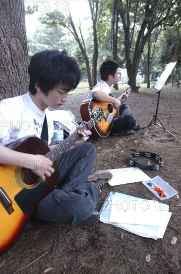 JAPAN, Honshu, Tokyo, "Yoyogi Park Harajuku. Yuki Nakagawa and Yousuke Koyama, both 15 years old, meet here on Saturday afternoons to practice guitars and sing "
