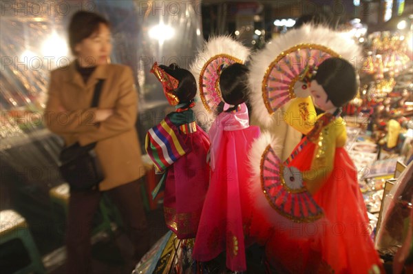 KOREA, Seoul, "Namdaemun Market on a cold December night with customer looking at sounvenir dolls dressed in traditional Korean ""hanbok"""