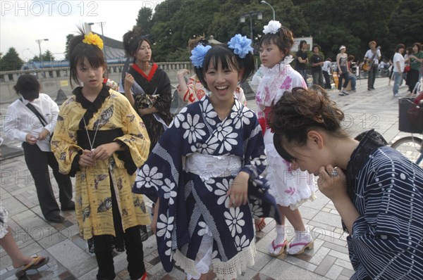JAPAN, Honshu, Tokyo, Harajuku. Members of Kyoto Rokumeikan relax after dancing at the entrance of Yoyogi Park dressed in half kimono costumes on Saturday afternoon