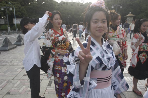 JAPAN, Honshu, Tokyo, Harajuku. Members of Kyoto Rokumeikan relax after dancing at the entrance of Yoyogi Park dressed in half kimono costumes on Saturday afternoon