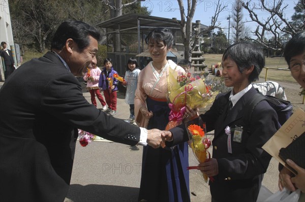 JAPAN, Chiba, Tako, "12 year old Satoshi Ui is congratulated by his principal, Mr. Saito, on his 6th grade graduation from Tako #3 Elementary School, his teacher Mrs. Horikoshi stands in middle in Kimono"