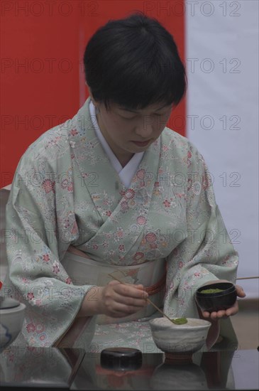 JAPAN, Chiba, Yokaichiba, "Licensed tea master, Chiharu Koshikawa, prepares green tea, ""macha"" at a tea ceremony and  places ""macha"" green tea powder in bowl"
