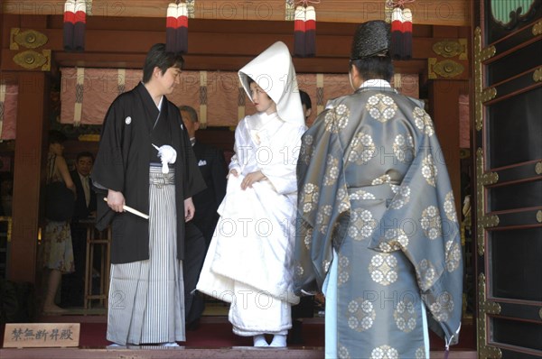 JAPAN, Honshu, Tokyo, "Nezu. Newlyweds after conclusion of Shinto ceremony at Nezu Jinja, both in traditional costume, while a Shinto priest waits for them"