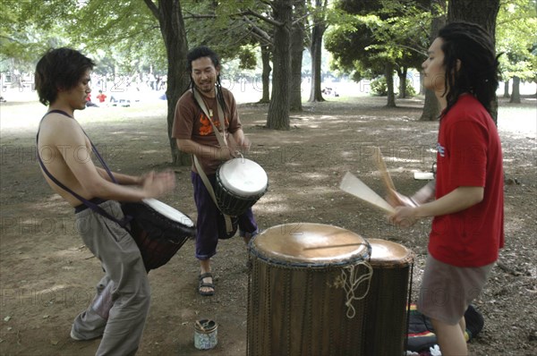 JAPAN, Honshu, Tokyo, "Harajuku. Yoyogi Park. Hiroaki Komura  and his brother Kenichi, with their friend Tomokazu Nagashima, playing African drums on a Saturday afternoon"