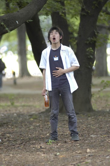 JAPAN, Honshu, Tokyo, "Harajuku. Masafumi Suzuki, 20 year old student at Japan Narration Technical School, does vocal exercises in Yoyogi Park on a Saturday afternoon"