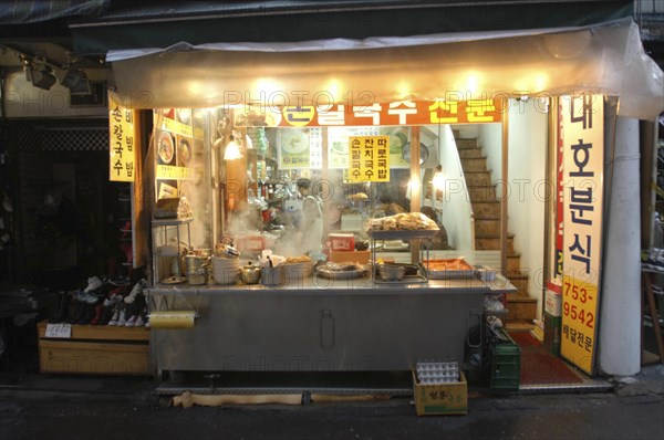KOREA, Seoul, Namdaemun Market at night in December. Streetside open restaurant with staff and customers