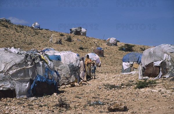 SOMALILAND, Hargeisa, The Kandahr IDP camp for Internally Displaced Persons.  Women and child standing between huts on barren hillside.