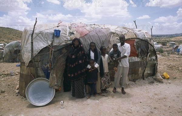 SOMALILAND, Hargeisa, The Kandahr IDP camp for Internally Displaced Persons.  Family standing outside traditional nomadic hut.