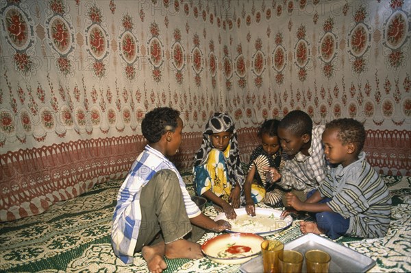 SOMALIA, Baidoa, Children eating meal at home from communal dish using the right hand.  At a family meal men are usually served first and women and children eat seperately later.