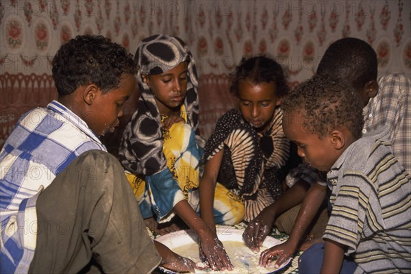 SOMALIA, Baidoa, Children eating meal at home from communal dish using the right hand.  At a family meal men are usually served first and women and children eat seperately later.