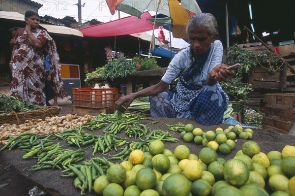 SRI LANKA, Colombo, "Pettah District. Female vendor selling limes, green chillies and vegetables"
