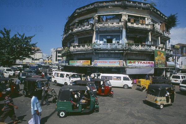 SRI LANKA, Colombo, "Pettah District. Busy street full of traffic including auto-rickshaws, taxis, minibuses and a steam roller.  Advertising hoardings on building behind."
