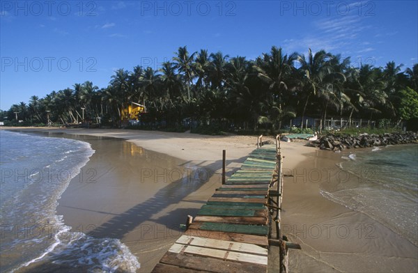 SRI LANKA, Mirissa, View along wooden jetty over the sea leading toward sandy beach