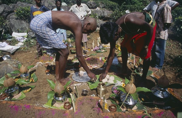 SRI LANKA, Haputale, Funeral ritual with son of the deceased with head shaved as a sign of bereavement and other mourners placing offerings on ground marked with coloured tika powder.