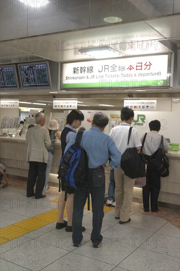 JAPAN, Tokyo , Tokyo station with customers waiting to buy Shinkansen aka bullet train tickets at a desk with bilingual signs above