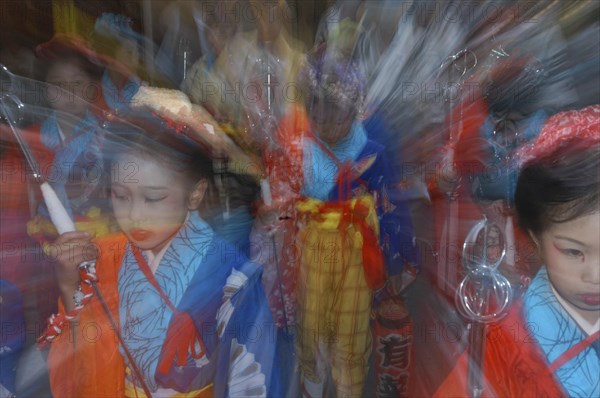 JAPAN, Chiba, Narita, Girls aged 8-12 years old in traditional Edo-era costumes lead their neighborhood's dashi or wagon through the streets during Gion Matsuri. Radial blur.