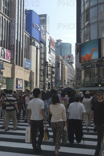 JAPAN, Honshu, Tokyo, Ginza. Pedestrian crossing and view along Chuo-dori avenue at the intersection with Harumi-dori avenue