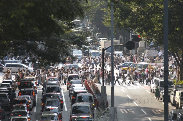 JAPAN, Honshu, Tokyo, "Harajuku. View looking up Omote-sando avenue to the intersection with Meiji-dori avenue with crowds on a pedestrian crossing, Saturday afternoon  "