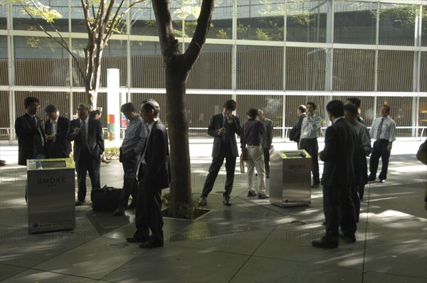 JAPAN, Honshu, Tokyo, "Yurakucho. A group of male salaried workers called salariman, smoking at a smoking station, during lunch hour at Tokyo International Forum  "