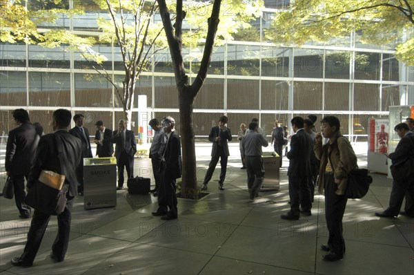 JAPAN, Honshu, Tokyo, "Yurakucho. A group of male salaried workers called salariman, smoking at a smoking station, during lunch hour at Tokyo International Forum  "