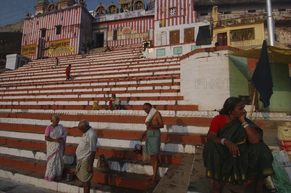 INDIA, Uttar Pradesh, Varanasi , Hindu worshippers on the steps of Kedar Ghat next to the Ganges River with steps leading up to Kedara Mandir temple in the early morning