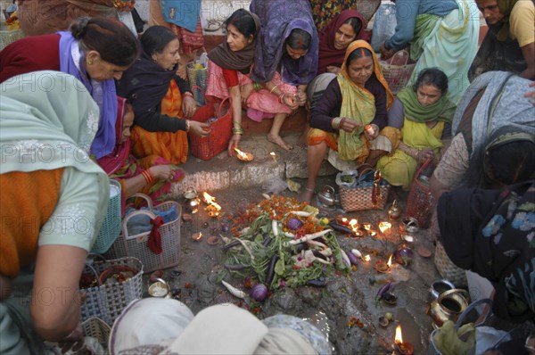 INDIA, Uttar Pradesh, Varanasi , Hindu women worship an earthen statue of the Hindu God Bhim at Asi Ghat beside the Ganges River