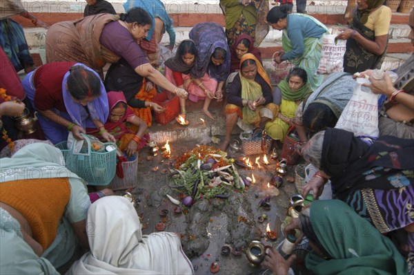 INDIA, Uttar Pradesh, Varanasi , Hindu women worship an earthen statue of Hindu God Bhim at Asi Ghat beside the Ganges River