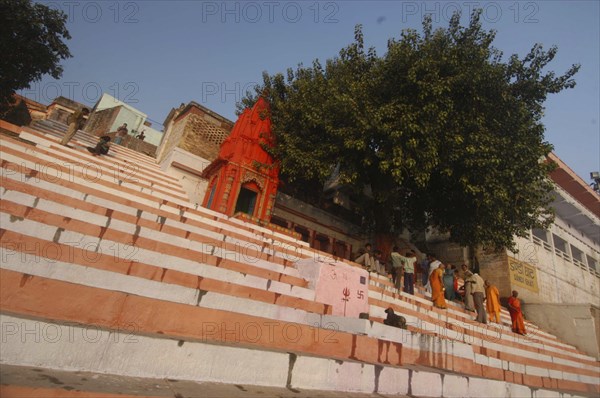 INDIA, Uttar Pradesh, Varanasi, Chauki Ghat steps leading up to a Shiva shrine with worshippers sitting under tree